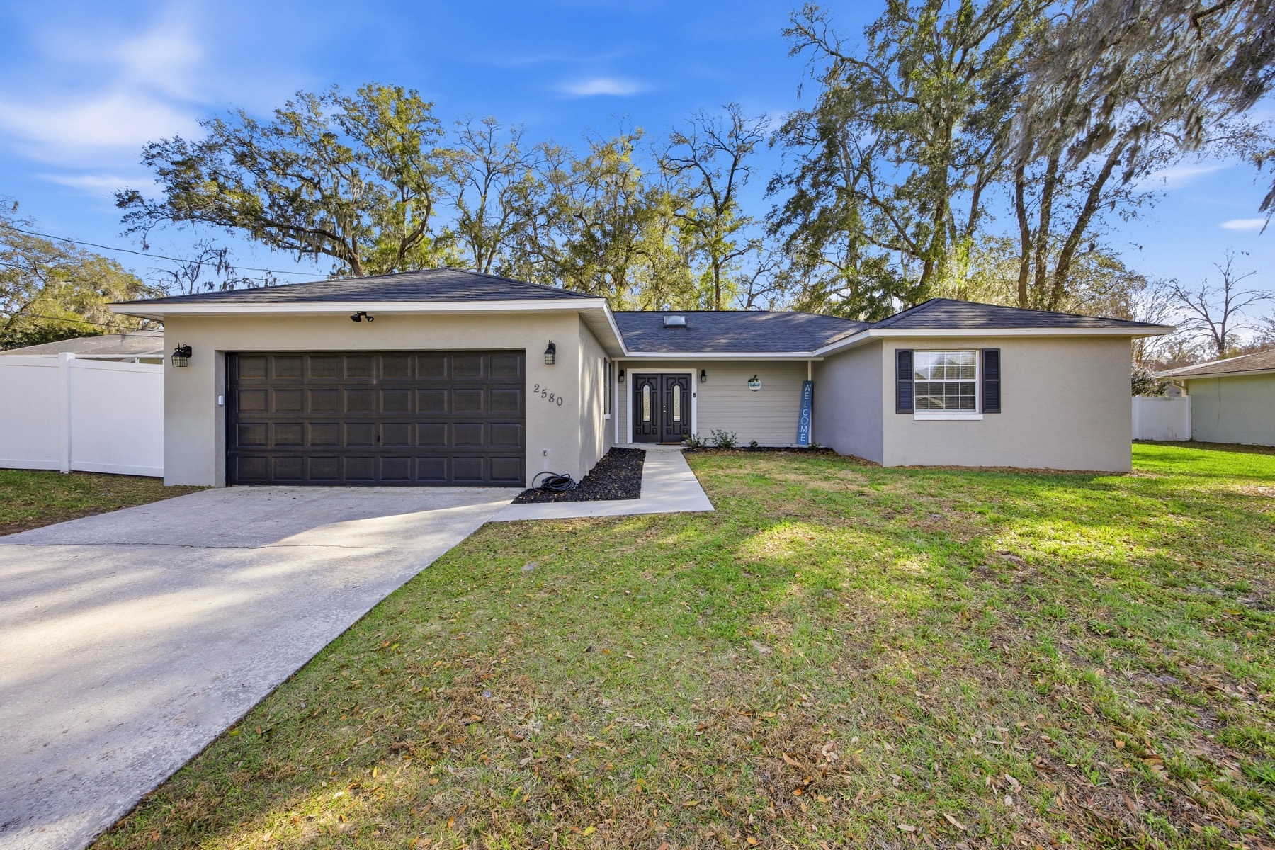 2580 SE 37th St Ocala FL 34471 - front exterior with garage, mature trees, and stucco finish in Shady Wood neighborhood