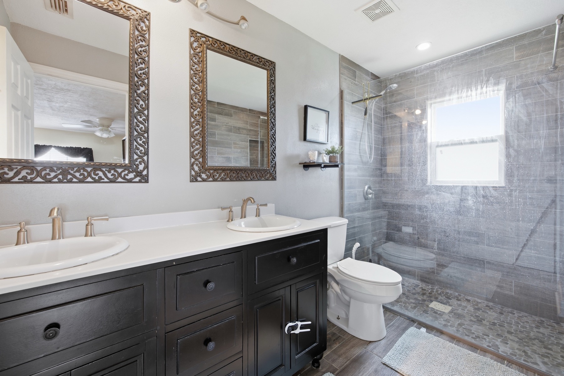 Updated primary bathroom with double vanity, ornate mirrors, and glass-enclosed shower at 2580 SE 37th St Ocala FL